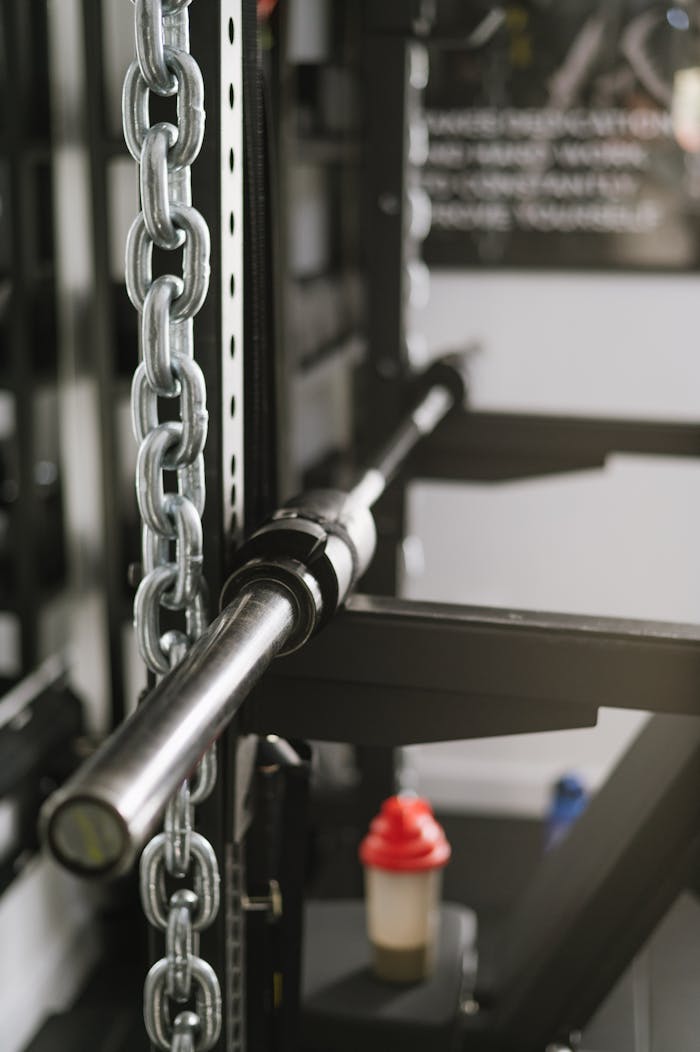 Close-up view of gym equipment including chains and a barbell, ideal for weightlifting and bodybuilding.
