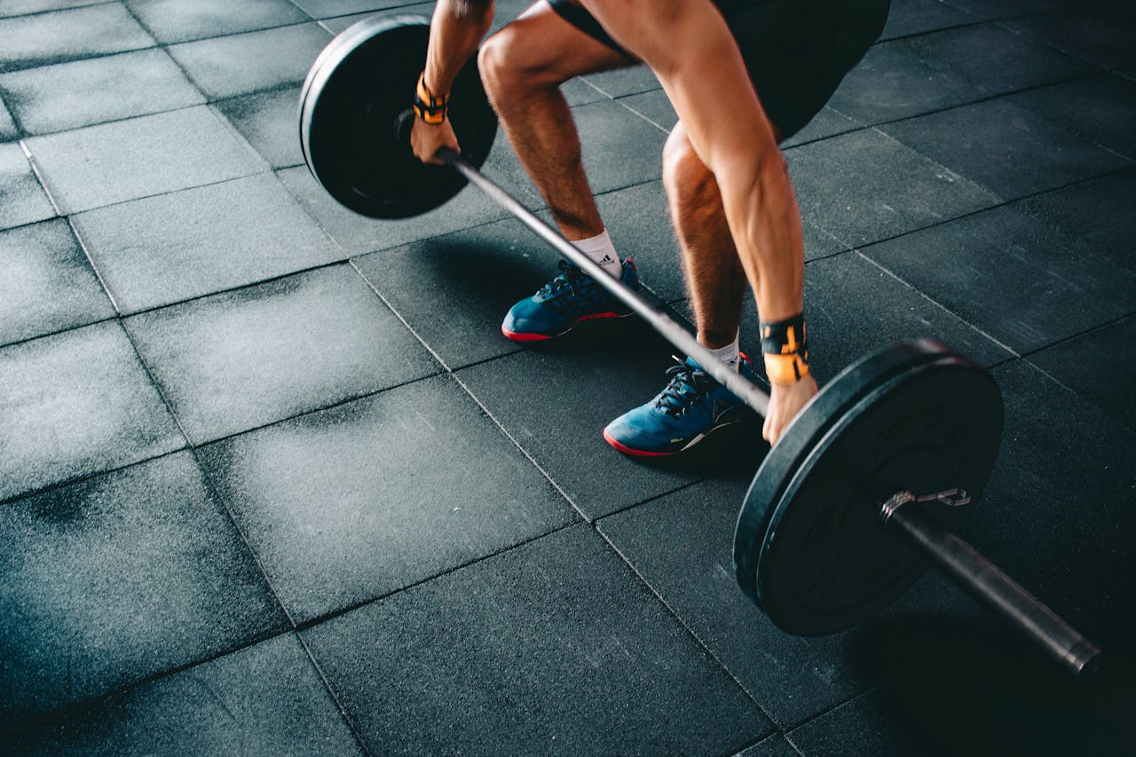 Young man lifting a heavy barbell during an intense indoor gym workout.